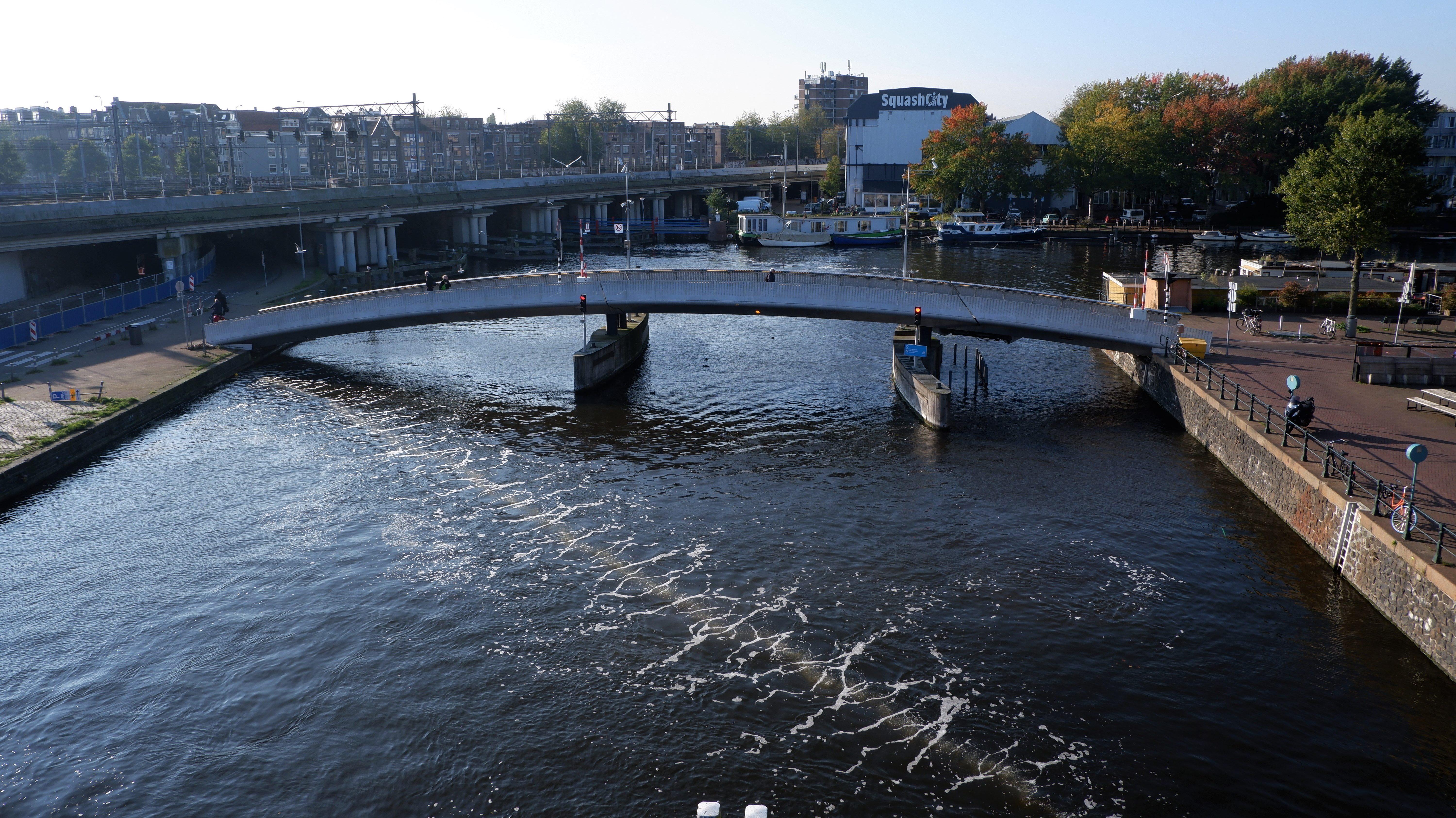 Bij de Han Lammergsbrug in het Westerdok borrelen in het water langs een diagonale lijn bubbels omhoog.