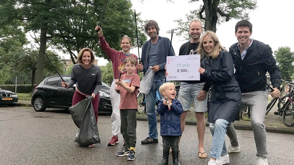 Een groepje bewoners poseren met de tweede prijs van de competitie de Schoonste Straat van Bos en Lommer ter waarde van 500 euro en afvalgrijpers.